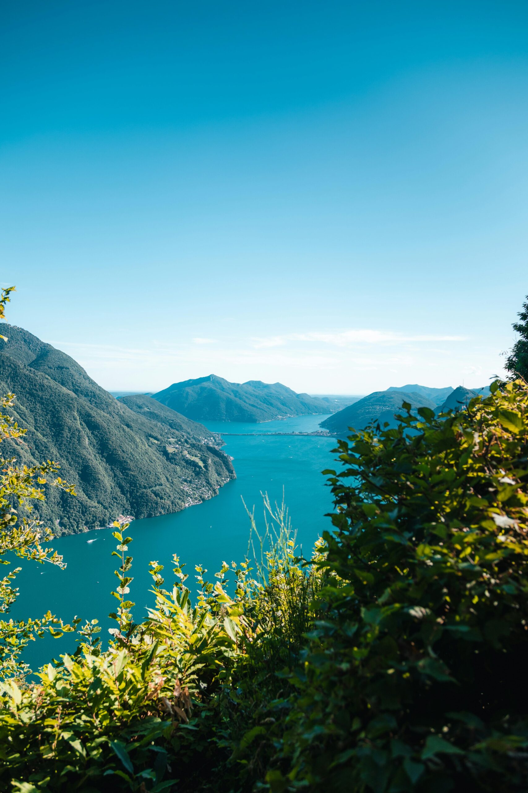 Breathtaking view of Lake Lugano with the Swiss Alps in the background, captured on a clear summer day.