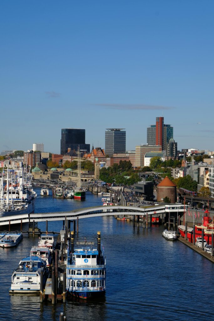 A scenic view of a bustling city harbor with boats and skyscrapers under a clear blue sky.