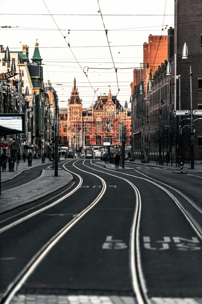 Urban scene with tramlines leading to Amsterdam Central Station during daytime.